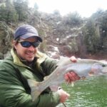 Man holds rainbow trout in Colorado while fly fishing