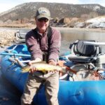 Man holds brown trout while fly fishing the Colorado River