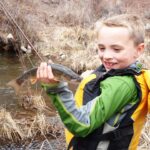 Child holds a brown trout caught while float fishing the Colorado River
