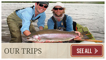 Man holds large rainbow trout with friend while fly fishing