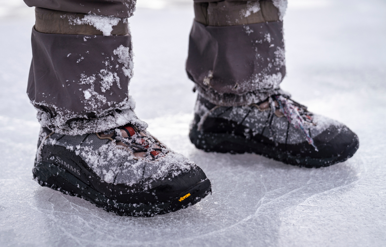 an angler stands on ice with rubber sole wading boots