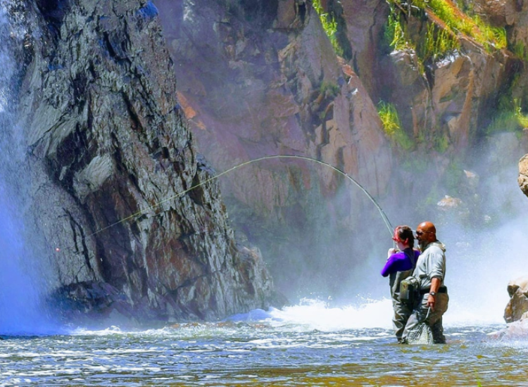 Man and women stand next to each other while fly fishing