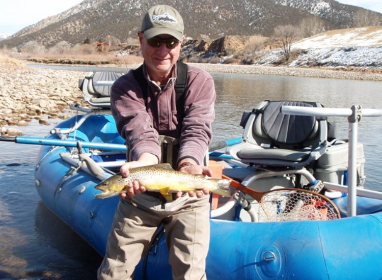 man holds brown trout that he caught while float fishing the Colorado River