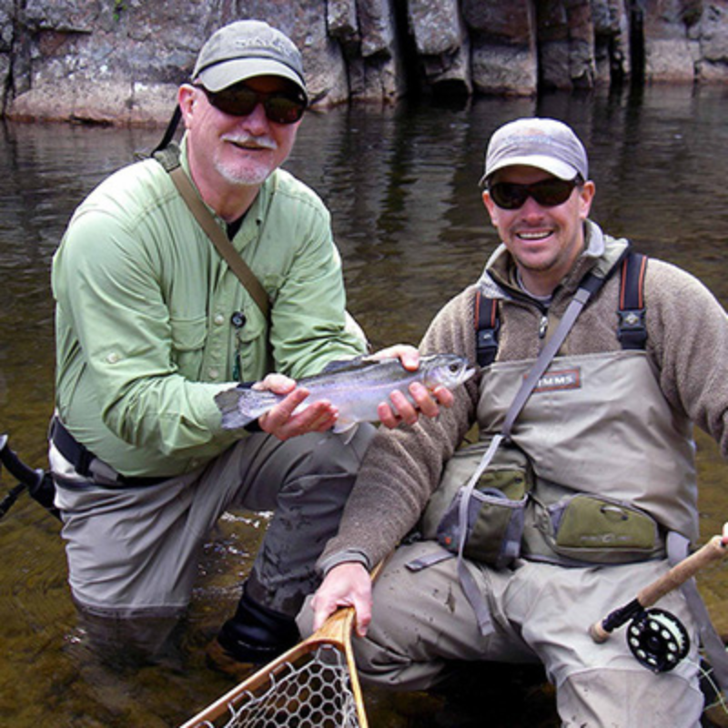 Private stream fly fishing two anglers hold a rainbow trout while fly fishing in Colorado