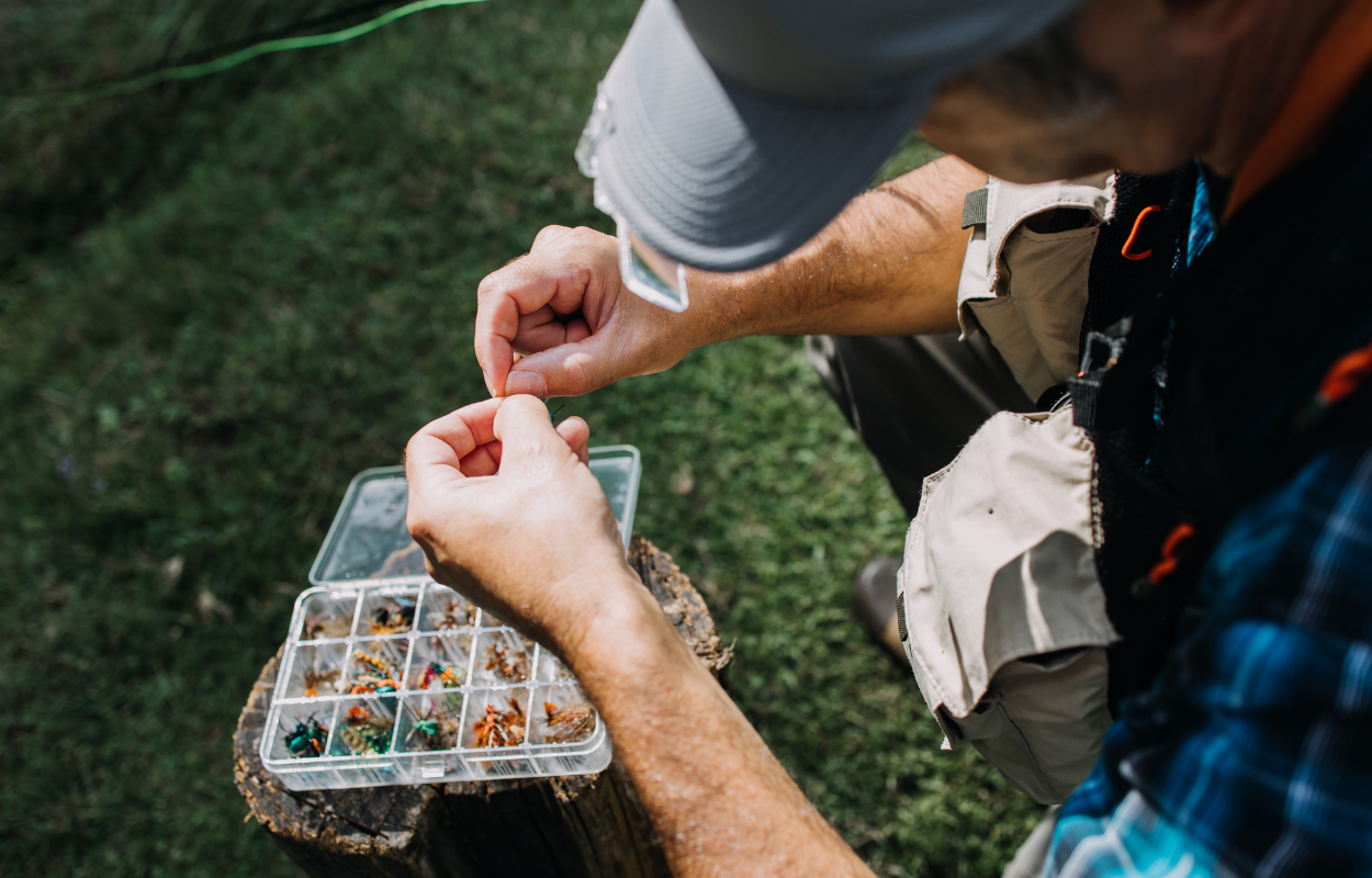 angler chooses a fly from a box full of fly fishing flies