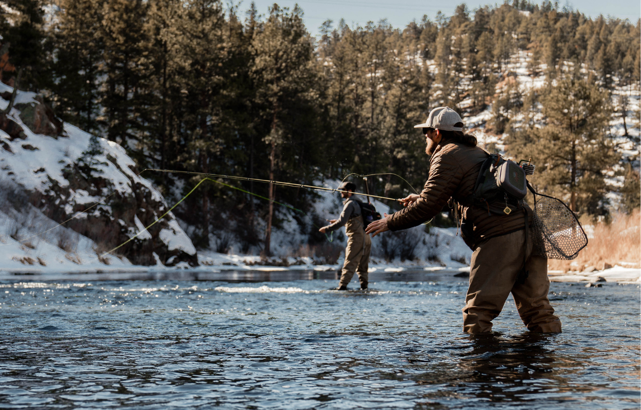 two men fly fish in a small stream during winter time