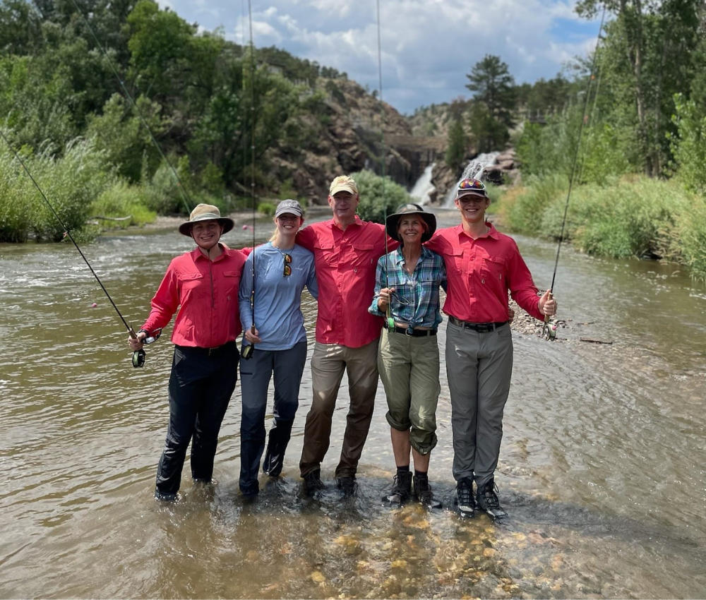 a group of anglers stand next to each other on the river