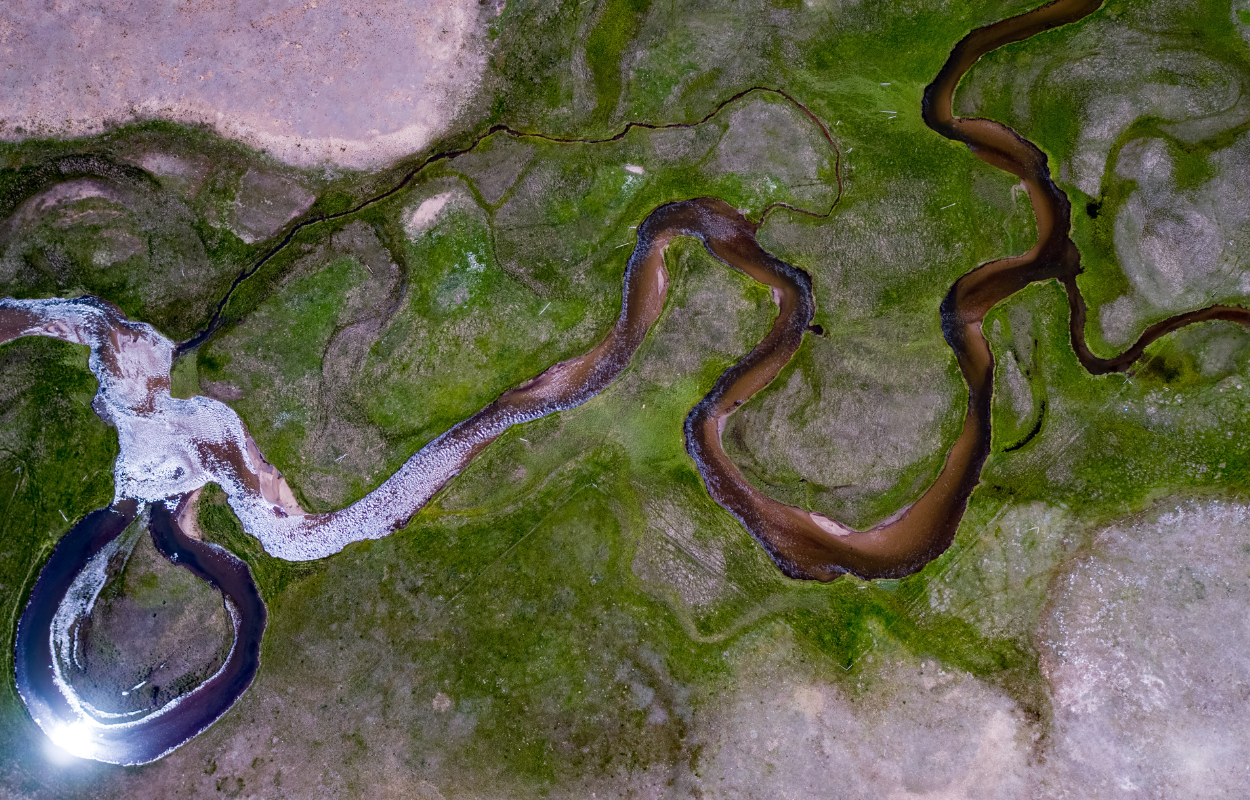 a winding river in a green field