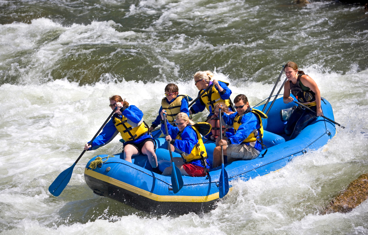 a group of people rafting in a blue raft on whitewater