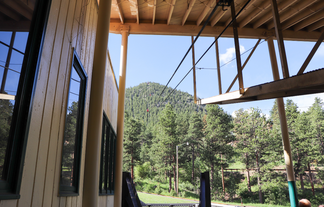 the inside of a structure looking up a forested mountain