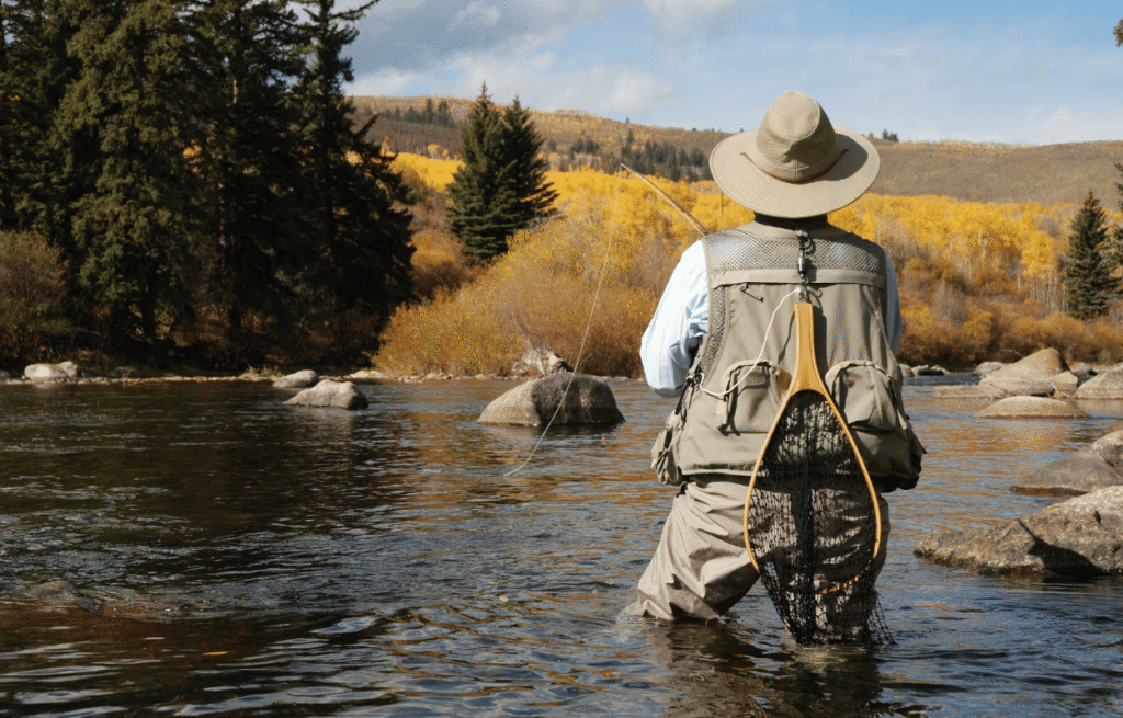 Man standing in river fly fishing in colorado. 