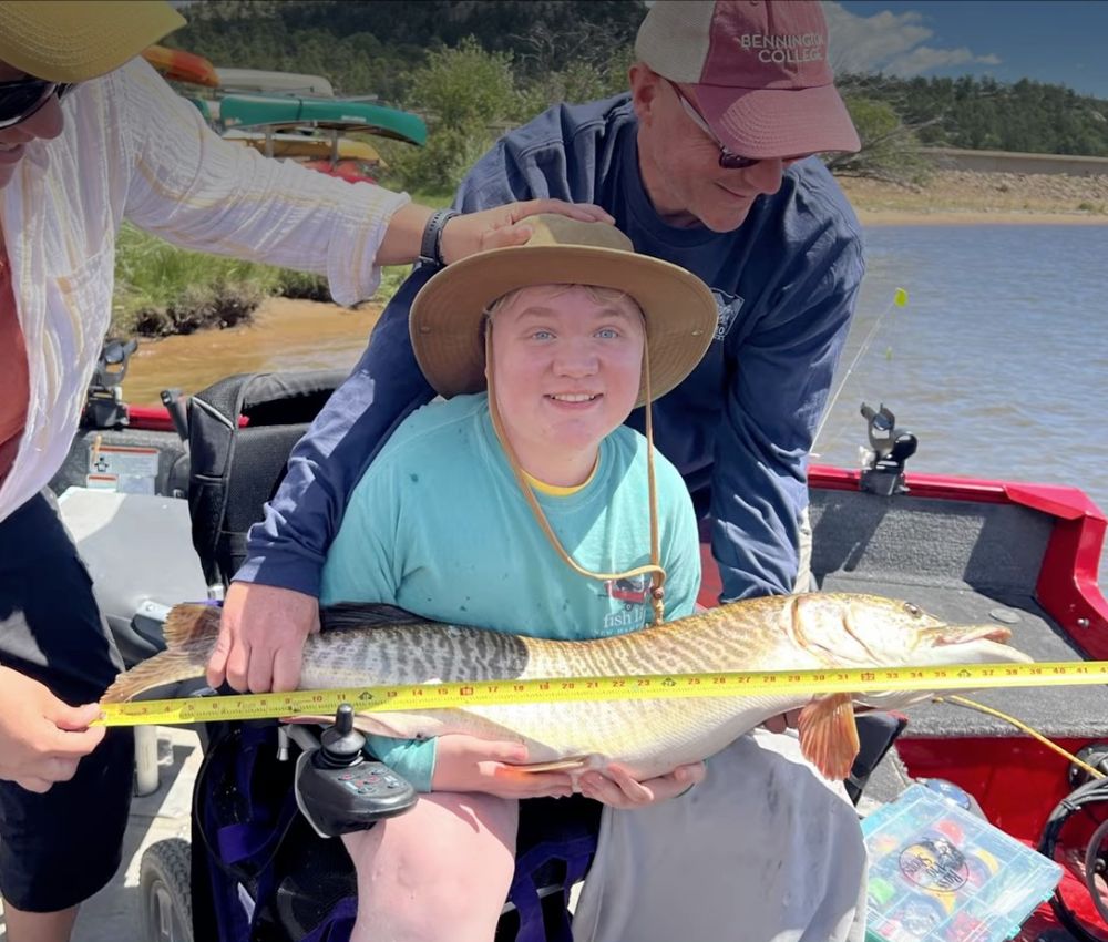 A person holding a fish on a boat in a wheelchair