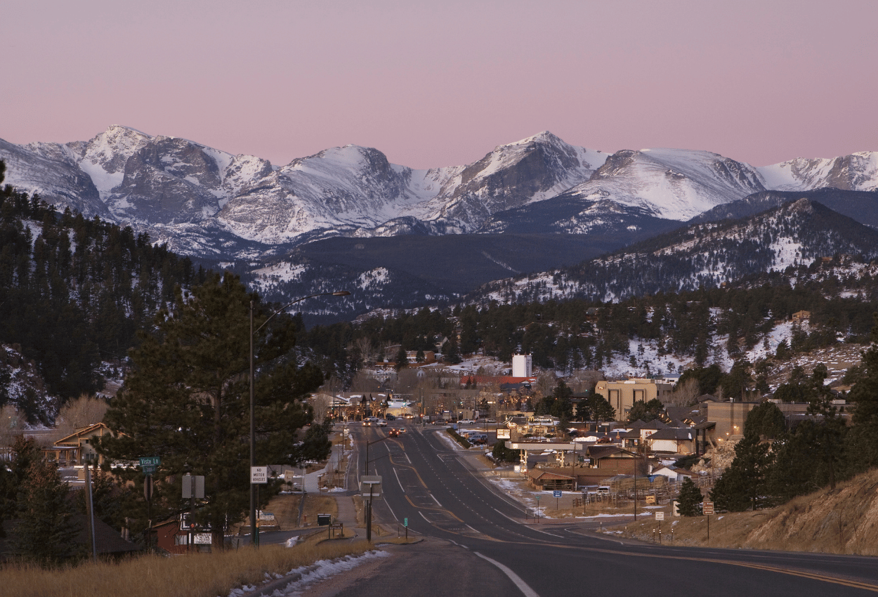Estes park downtown area and road with snowy mountains in background.