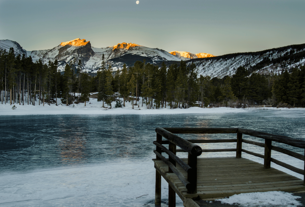 Sunset mountains and a frozen lake at sprague lake in the national park.